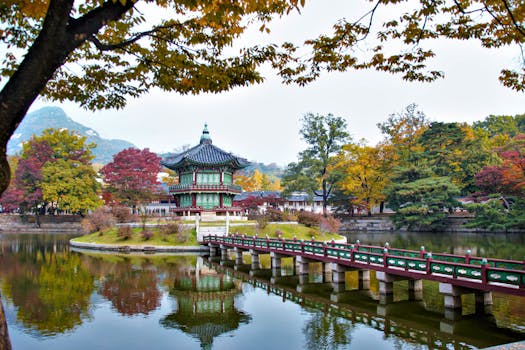 Tranquil autumn scene at Gyeongbokgung Palace with colorful trees and a serene lake reflection.